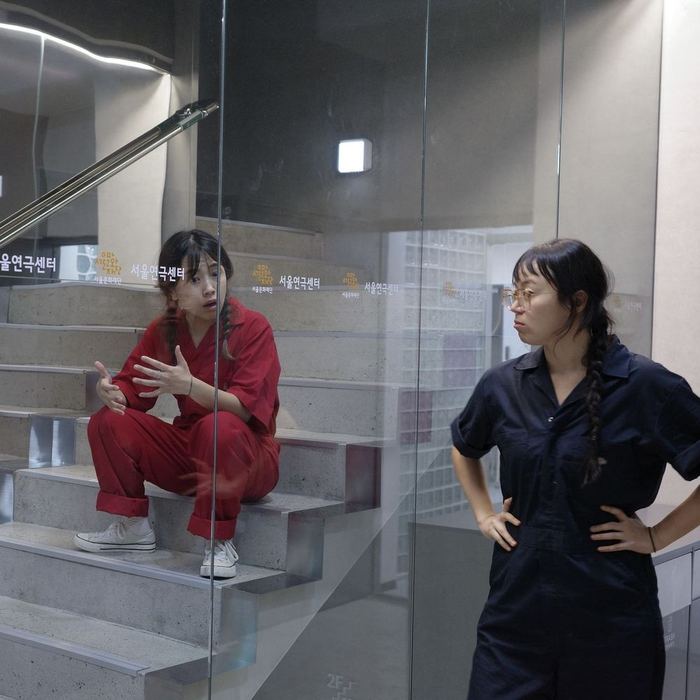 Two performers separated by a glass wall during A Tale of Miners of Mind